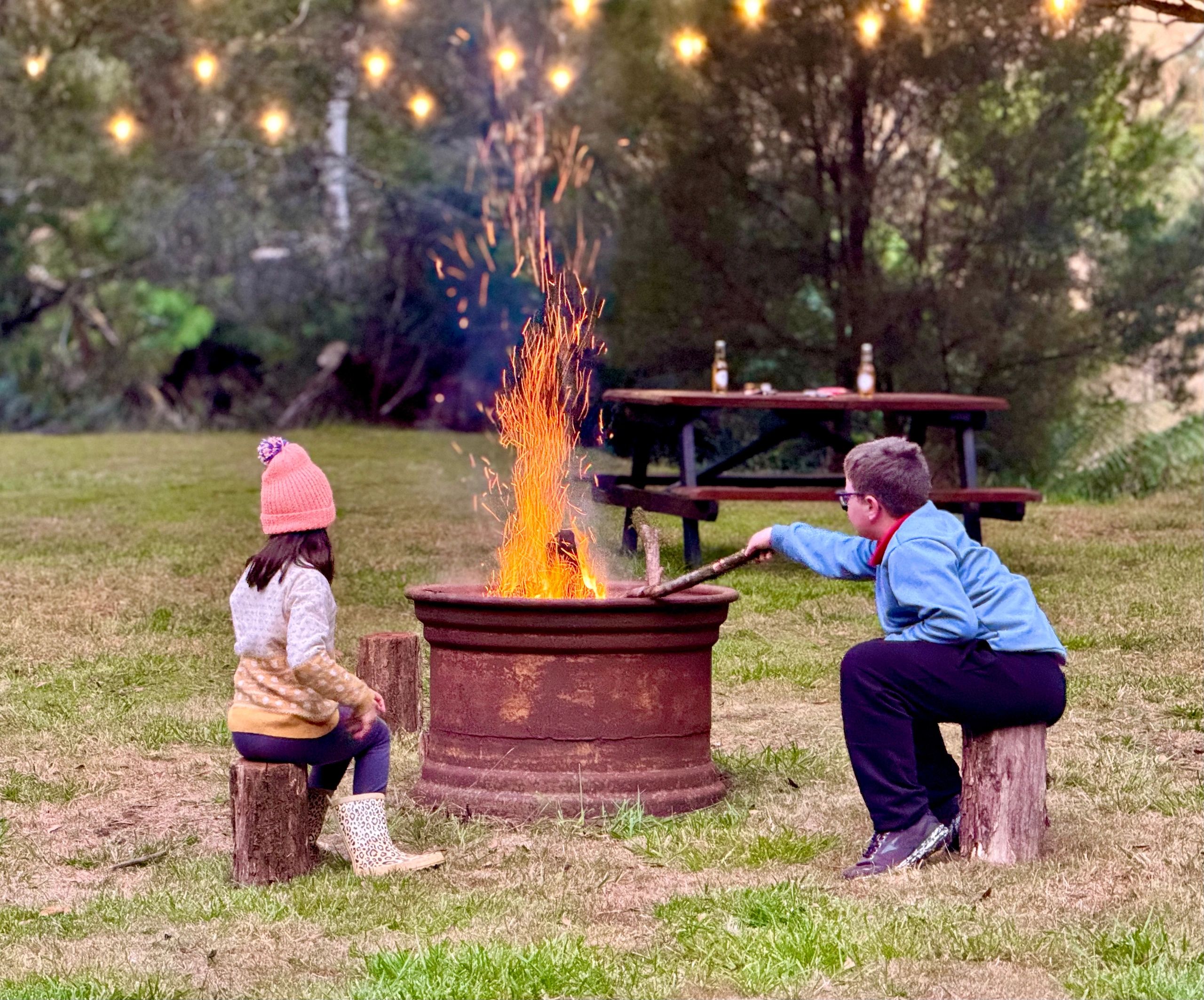 Children around campfire with string lights